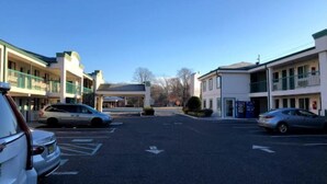 A parking lot with cars, a building with a flat roof, and a clear sky. - Garden State Inn (Absecon)
