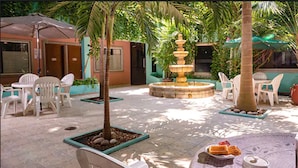 Une cour avec des sièges en plein air, une fontaine et une table où sont servis des plats et des boissons.
