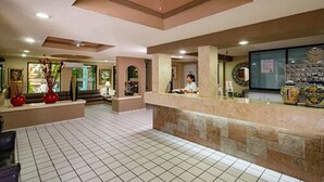 Un hall d’hôtel avec un comptoir d’accueil, une horloge et un sol carrelé.