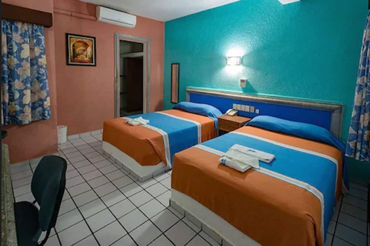 Ein Hotelzimmer mit zwei Betten, einem Schreibtisch, einem Stuhl und einer Badezimmertür.