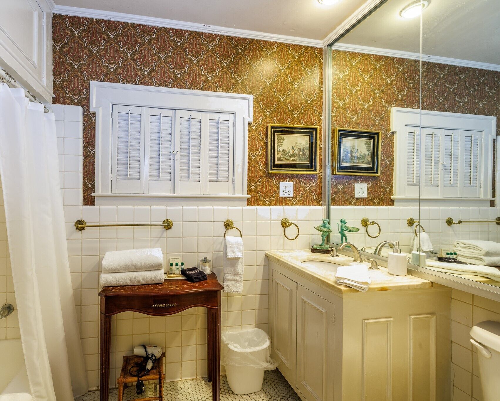 Une salle de bain équipée d’un meuble-lavabo, d’un lavabo et de toilettes. On y trouve des serviettes et des articles de toilette sur le meuble-lavabo.