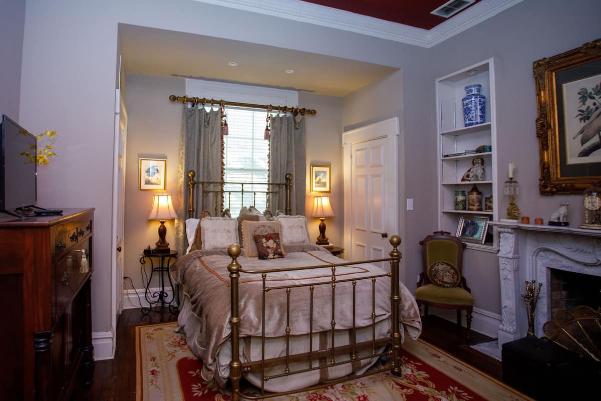 A bedroom with a four-poster bed, a fireplace, and a bookshelf.