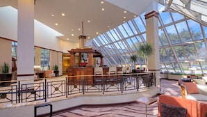 A spacious lobby with a high ceiling, large windows, and a central seating area. - Hilton Houston Westchase (Houston)