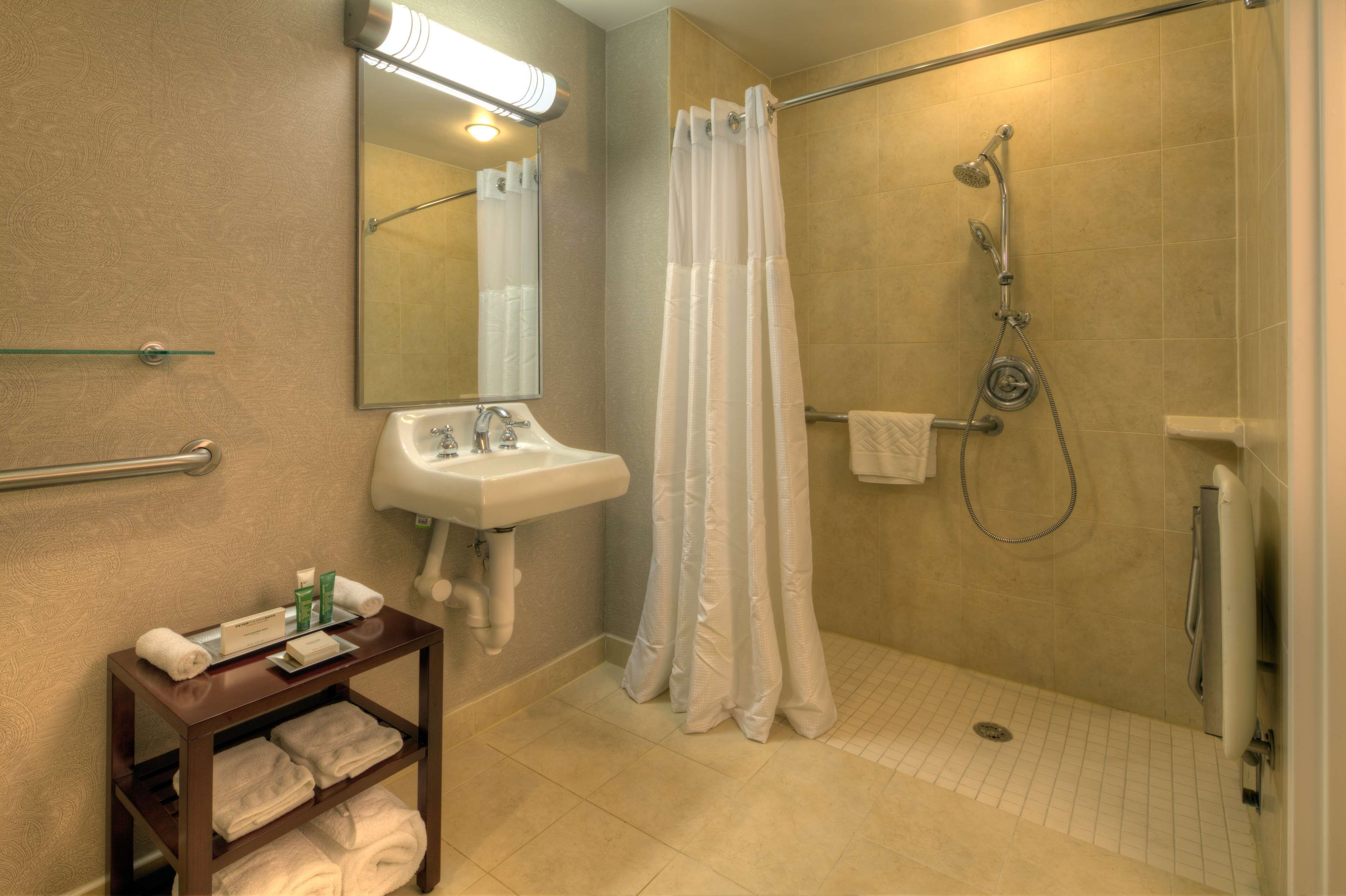 Une salle de bain équipée d’une douche, d’un lavabo et d’un porte-serviettes avec des serviettes.