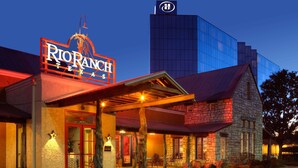A hotel with a prominent sign reading "RIO RANCH TEXAS" and a modern glass building in the background. - Hilton Houston Westchase (Houston)