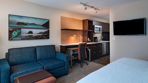 A hotel room with a sofa, a desk, a bed, a TV, and a kitchen area. - TownePlace Suites by Marriott Tacoma Lakewood (Lakewood)