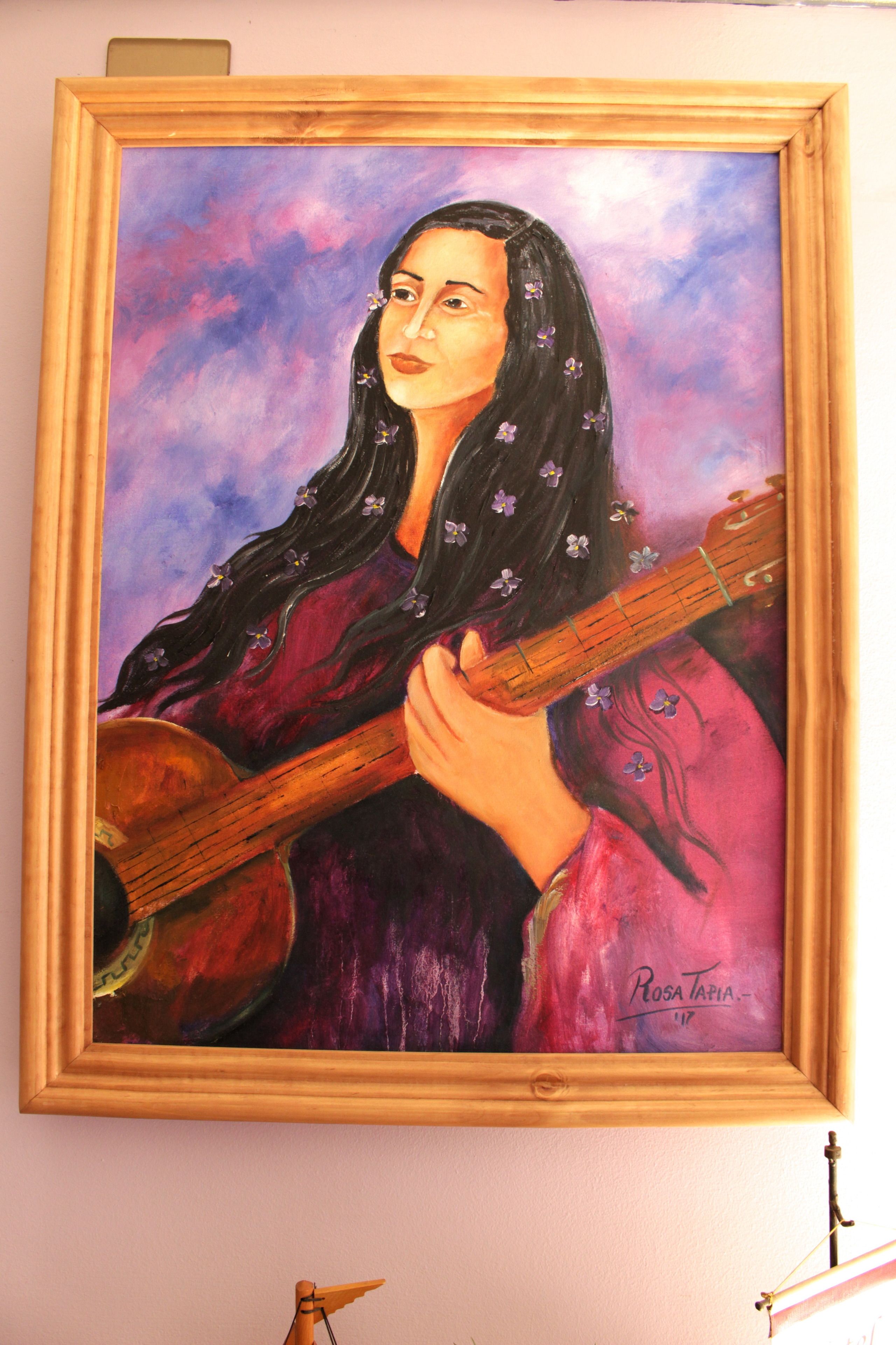 Uma pintura emoldurada de alguém tocando violão.