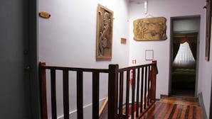 Un pasillo con barandillas de madera, suelo de madera y obras de arte en las paredes.