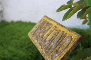Un gros plan d’un panneau jaune avec du texte gravé, partiellement masqué par le feuillage vert.