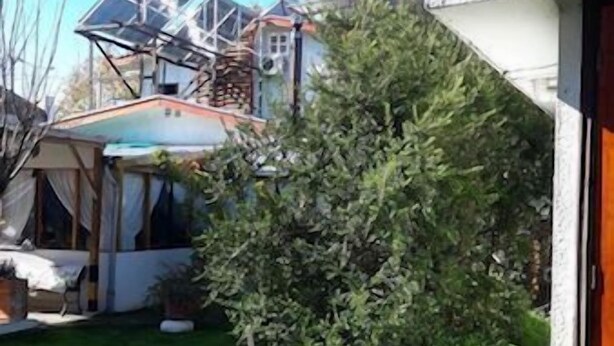 Un barrio residencial con un césped cuidado, un jardín pequeño y una casa con una chimenea visible.