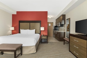 A hotel room with a bed, bedside tables, a TV, a desk, and a kitchenette. - Best Western Plus Merritt Hotel (Merritt)