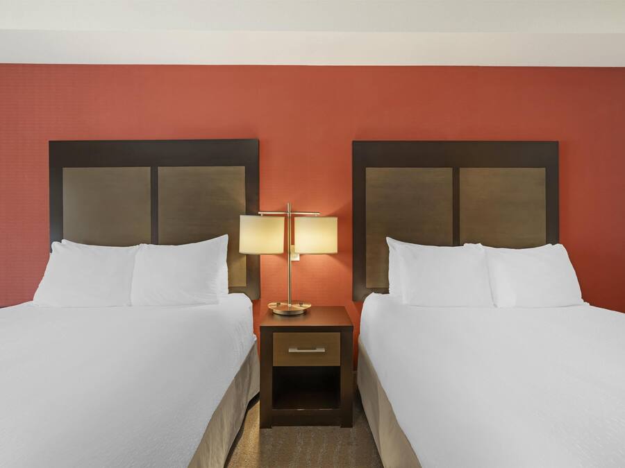 Ein Hotelzimmer mit zwei Betten, einem Nachttisch und einer Wandleuchte.
