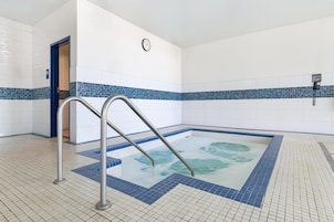 Una piscina con un reloj en la pared, un teléfono y un borde con azulejos azules.