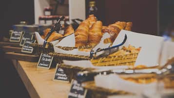 Eine Bäckerauslage mit verschiedenen Backwaren und Brot, darunter Croissants und Schokoladencroissants, mit Preisauszeichnungen.