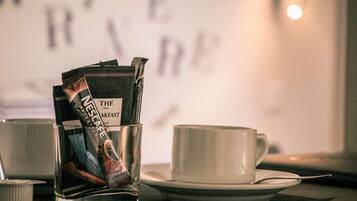 Un verre de café, un sachet de café et une tasse sur une table.