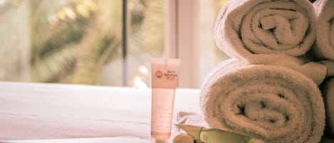 Un ordinateur portable est posé sur une table, à côté de serviettes enroulées et d’une bouteille de shampoing Best Western Plus.