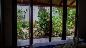 A room with a bed, a window with a view of a garden.