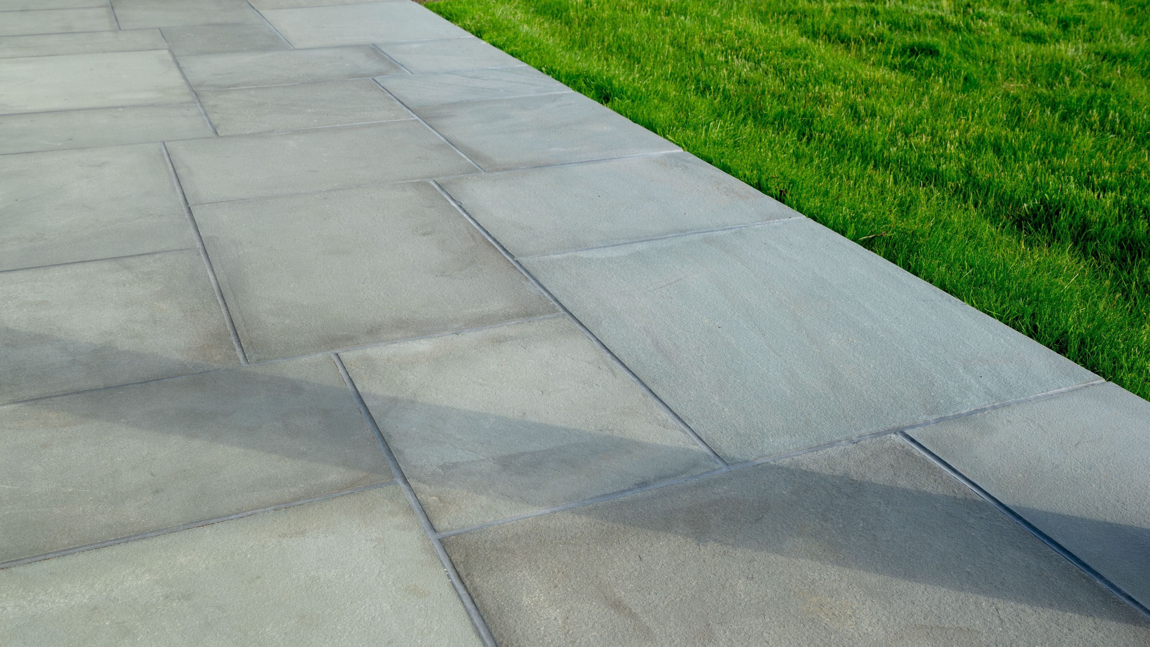 A paved walkway adjacent to a grassy area.