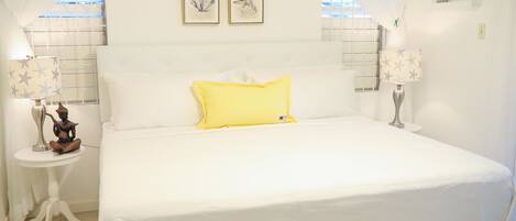 A neatly arranged bedroom with a bed, two bedside tables, and a window with curtains.
