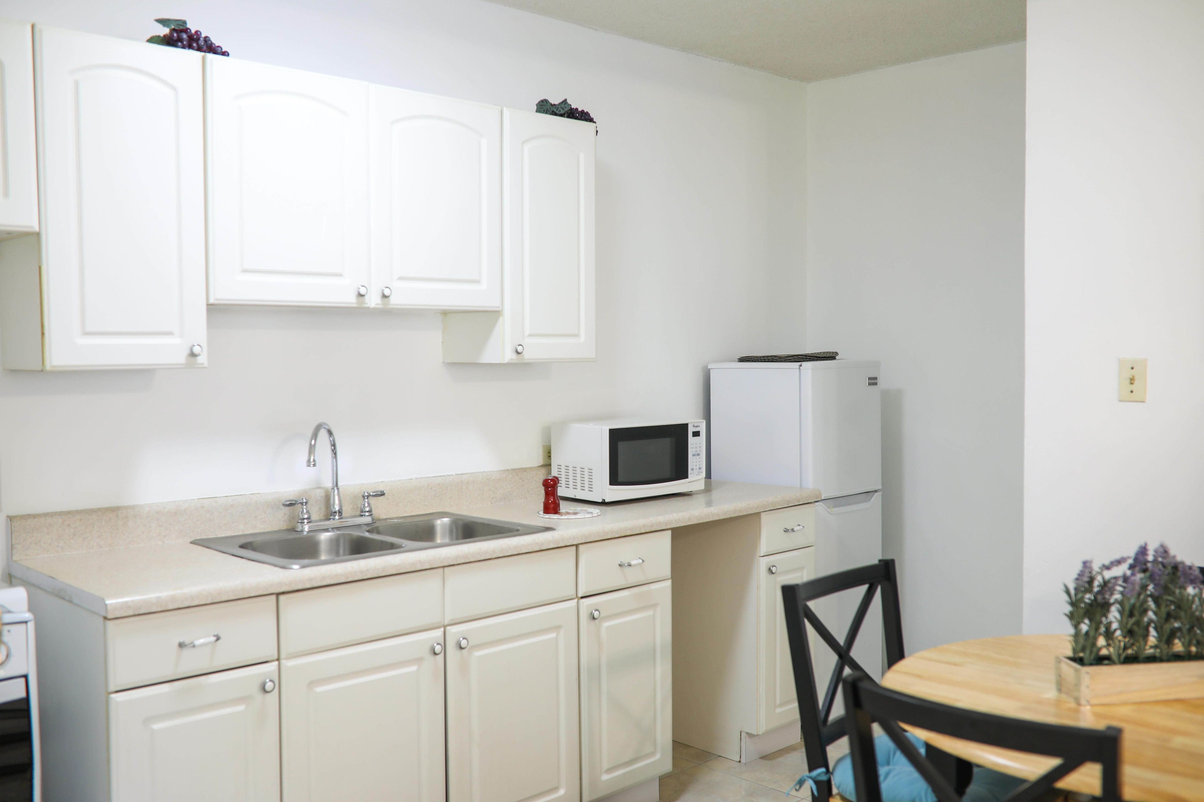 A kitchen with white cabinets, a microwave, a sink, and a refrigerator.