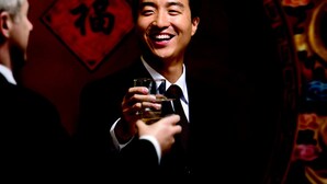 A person in a suit holding a glass, standing in front of a table with various dishes. - Holiday Inn Baoji Central by IHG (Baoji)