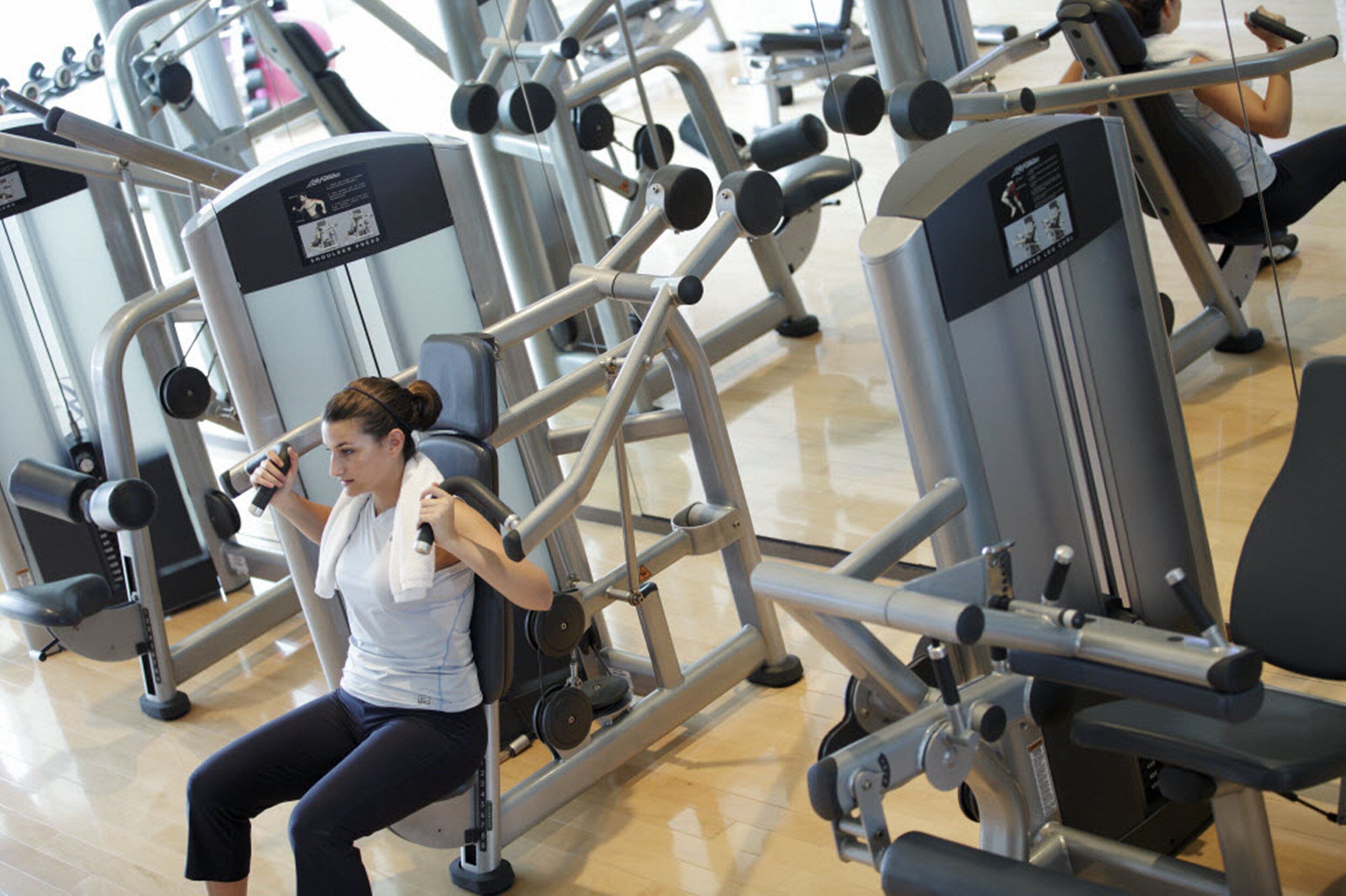 Un gimnasio con diversas máquinas de ejercicio, incluyendo una máquina de remo sentado y una prensa de piernas.