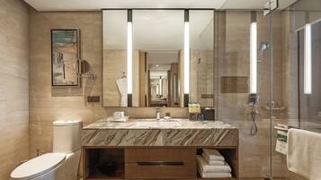 A modern bathroom with a marble sink, a large mirror, a glass shower enclosure, and a toilet.