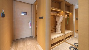 Ein Hotelzimmer mit Holzschrank, Spiegel und Sitzbank.