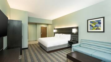 Una habitación de hotel con cama, sofá, televisión y escritorio.