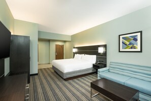 Ein Hotelzimmer mit Bett, Sofa, Fernseher und Schreibtisch.
