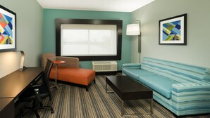 Une chambre d’hôtel moderne dotée d’une grande fenêtre, d’un canapé, d’une petite table et d’un bureau avec une chaise.