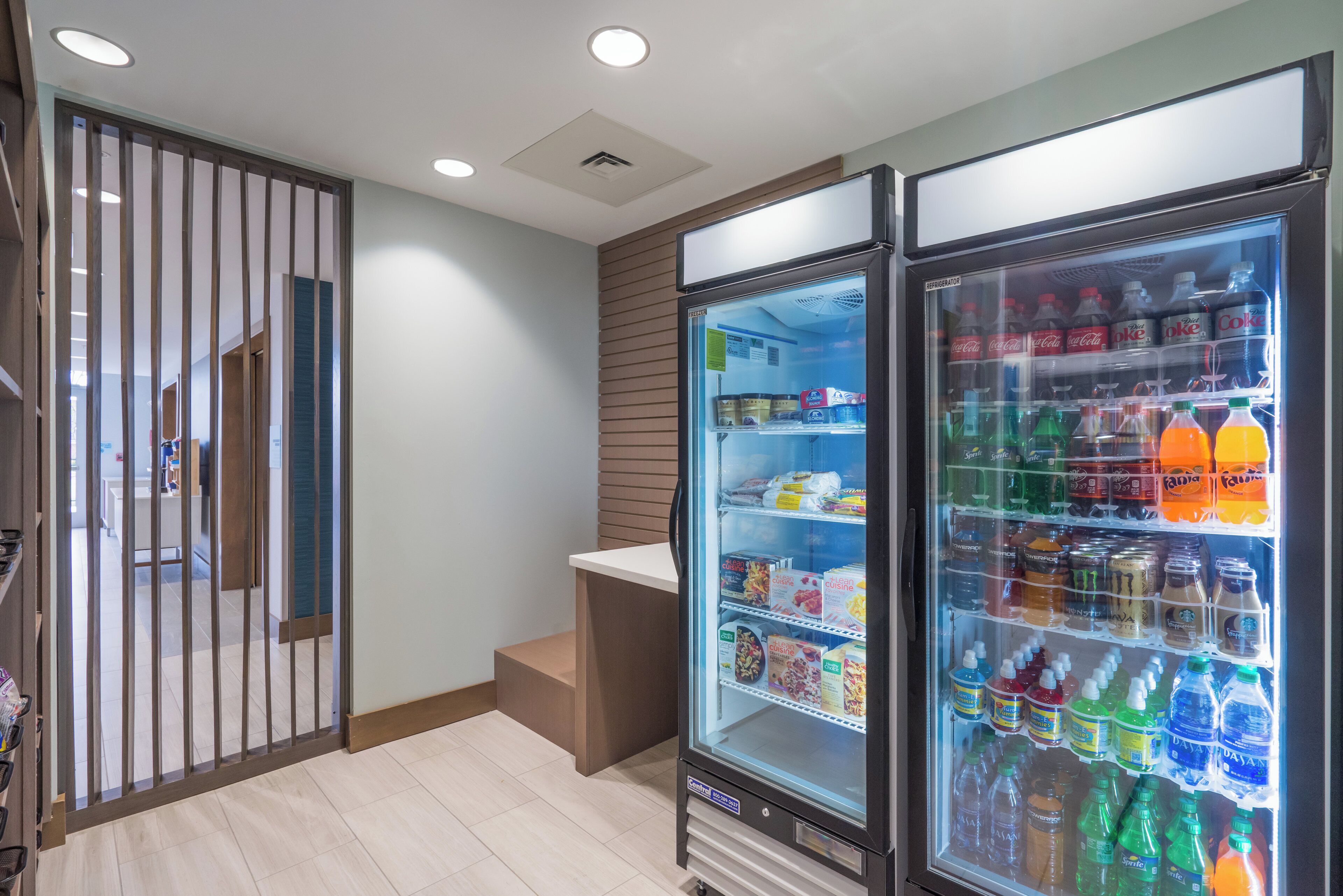 A kitchenette area with a refrigerator stocked with beverages and snacks, a microwave, and a small sink.