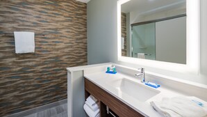 Une salle de bain moderne avec un grand miroir, un lavabo blanc et un meuble-lavabo en bois.