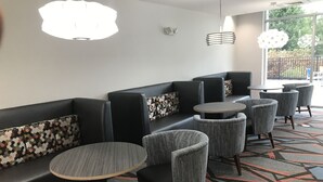 En moderne hotellobby med et siddeområde med sofaer og runde borde.