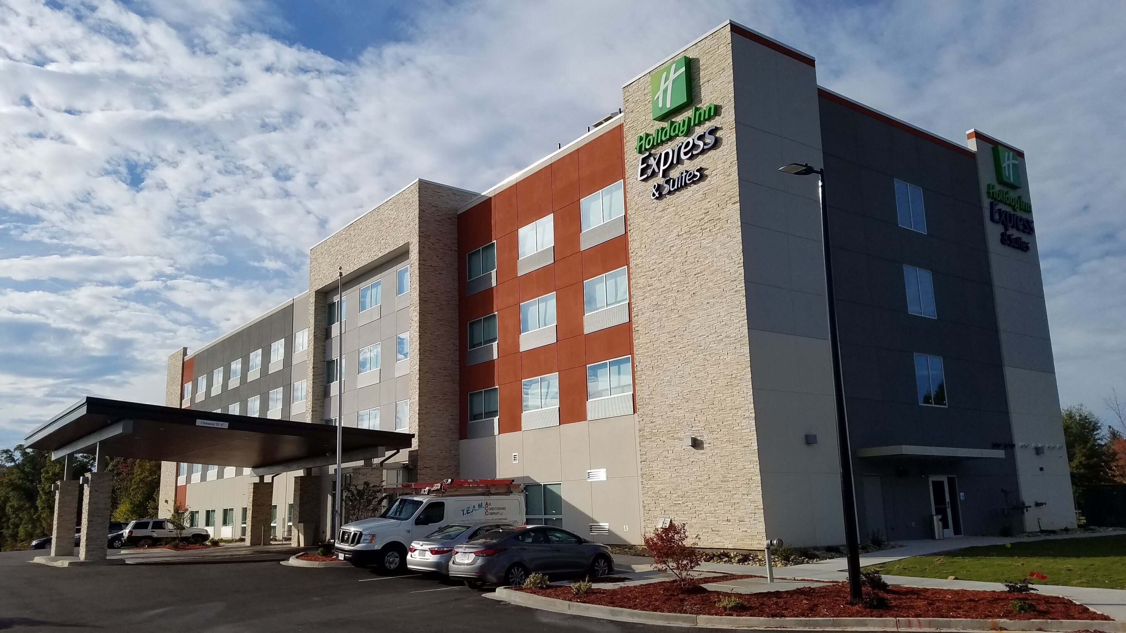 A Holiday Inn Express & Suites hotel with a brick facade, multiple windows, and a covered parking area.