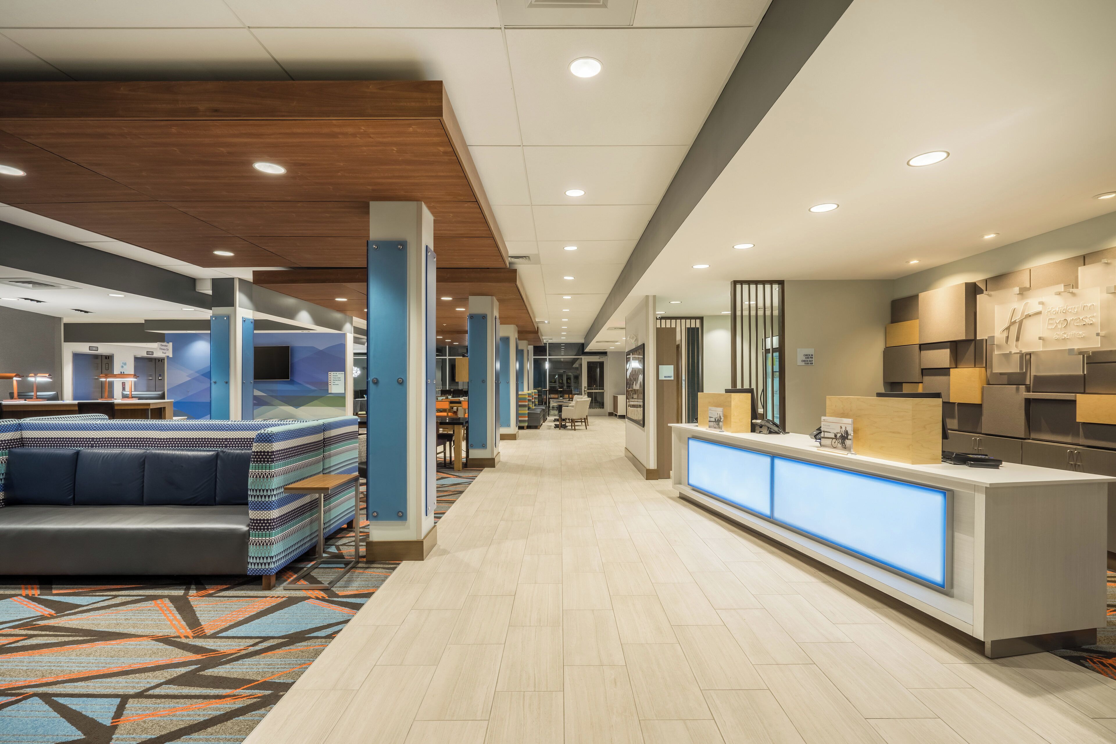 A hotel lobby with a reception desk, seating areas, and a corridor leading to other rooms.
