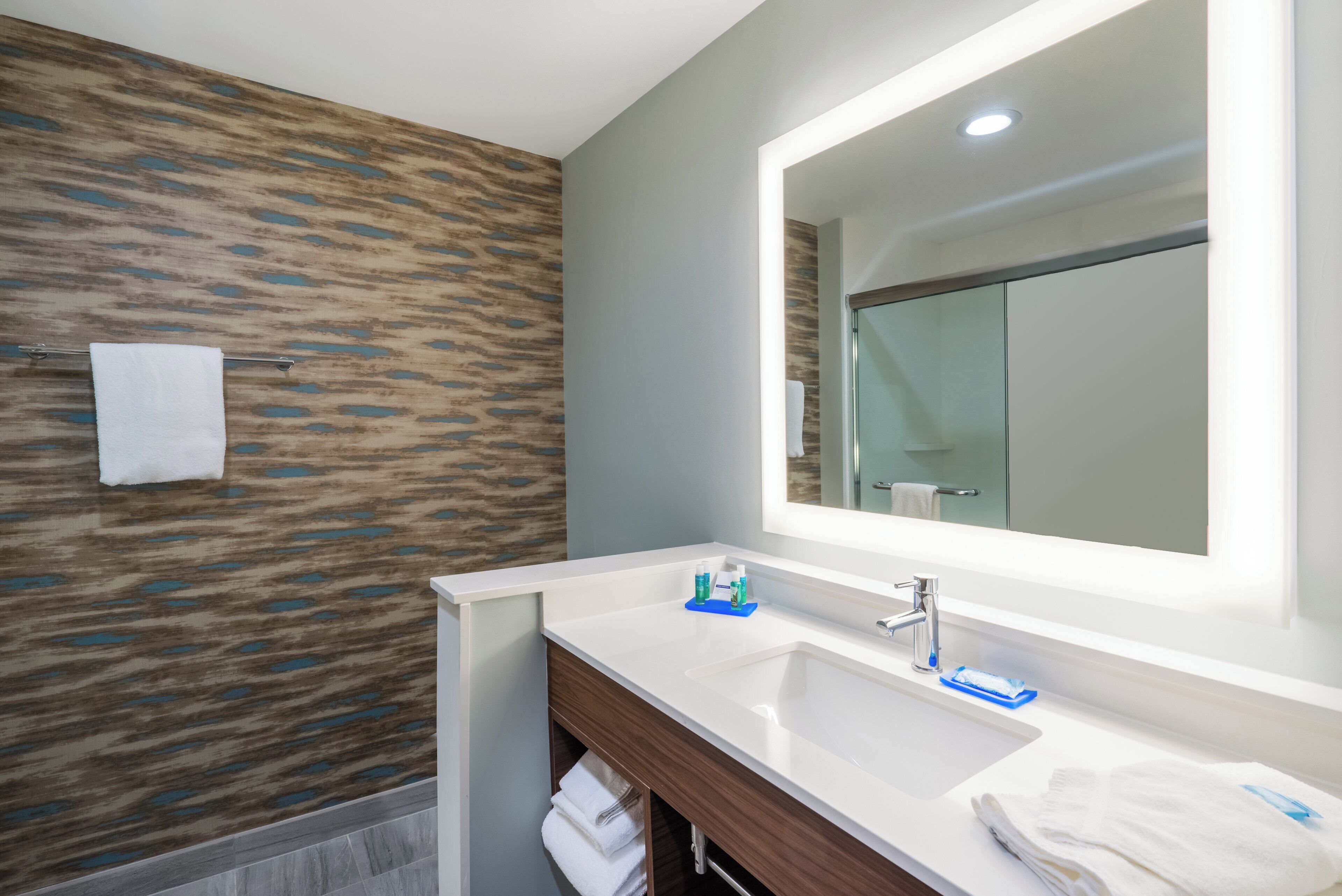 Un bagno moderno con un grande specchio, un lavandino e un portasciugamani.