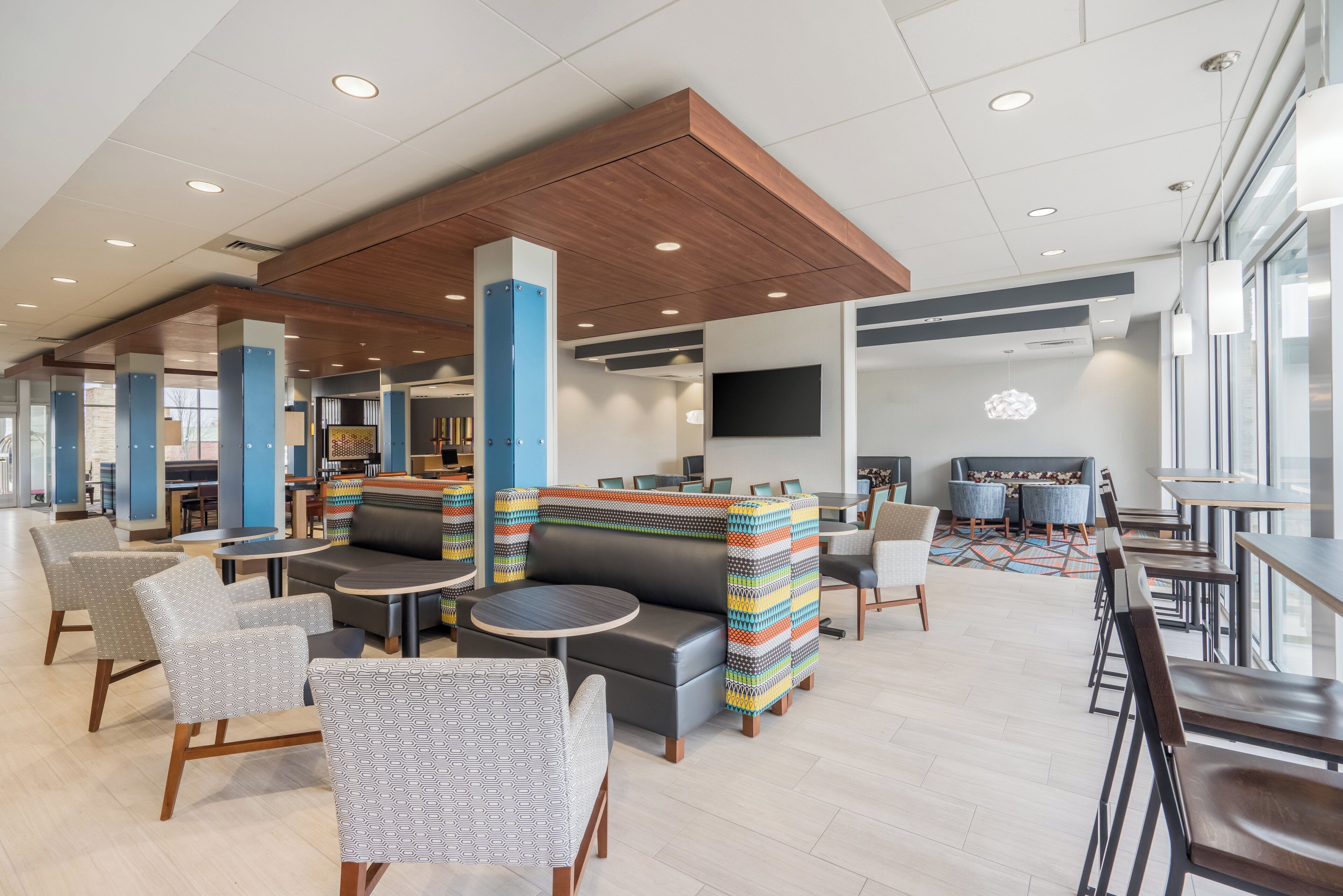 A modern lounge area with seating, tables, and a TV screen.