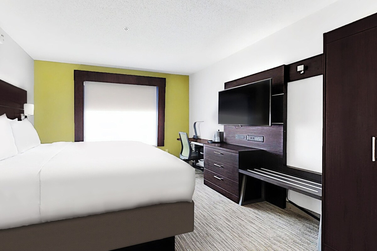 Een hotelkamer met een bed, bureau, televisie en kledingkast.