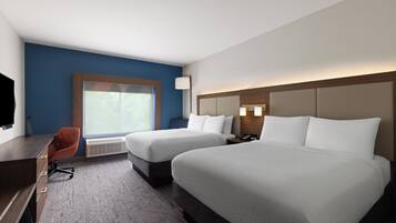 A hotel room with two beds, a desk, a chair, a TV, and a window.