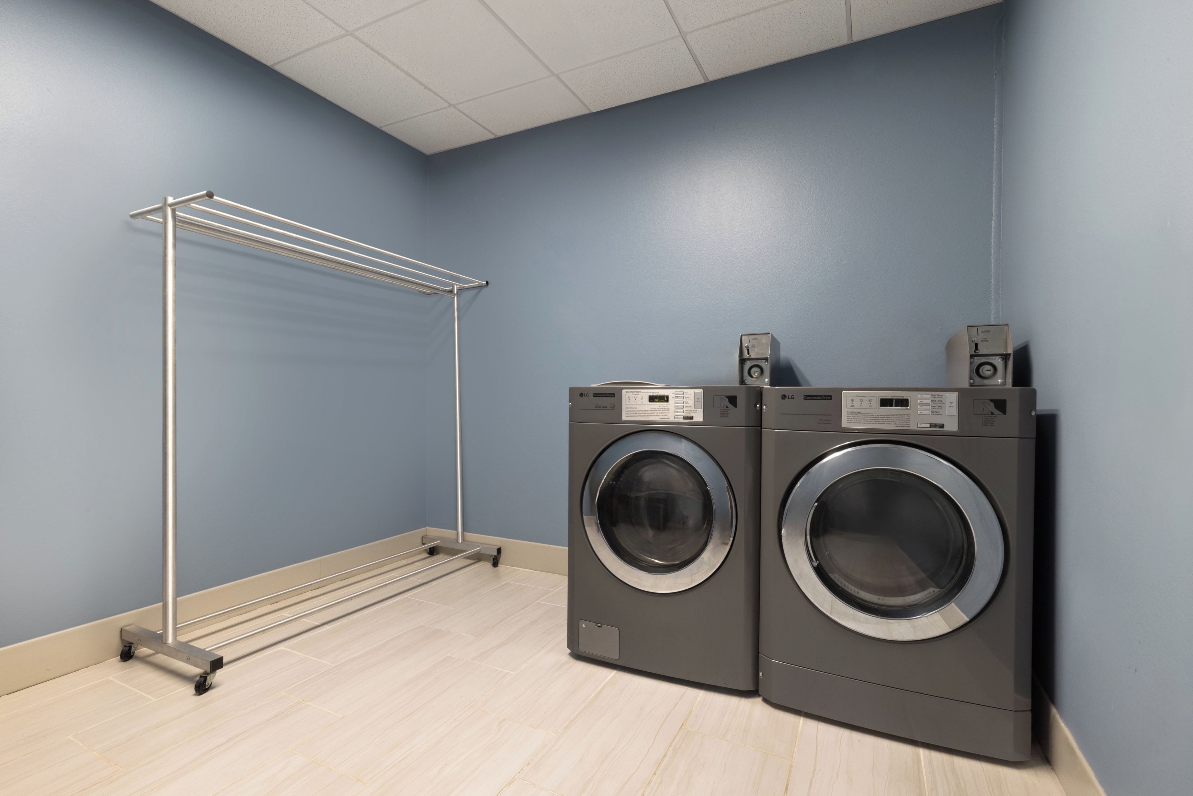 A laundry room with two front-loading washing machines and a drying rack.