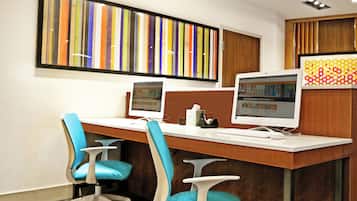 A modern office space with two desktop computers, a wooden desk, and two blue chairs.