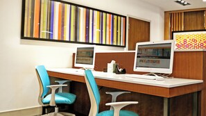 Un espace de bureau moderne comprenant deux ordinateurs de bureau, un bureau en bois et deux chaises bleues.
