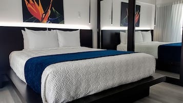 Una moderna camera d'hotel con un letto grande, un'area salotto separata e opere d'arte alle pareti.