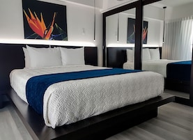 Una moderna camera d'hotel con un letto grande, un'area salotto separata e opere d'arte alle pareti.