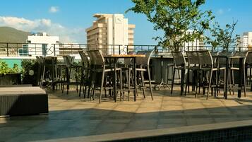 Relax by the pool with comfortable wicker chairs and tables in a casual, open layout.