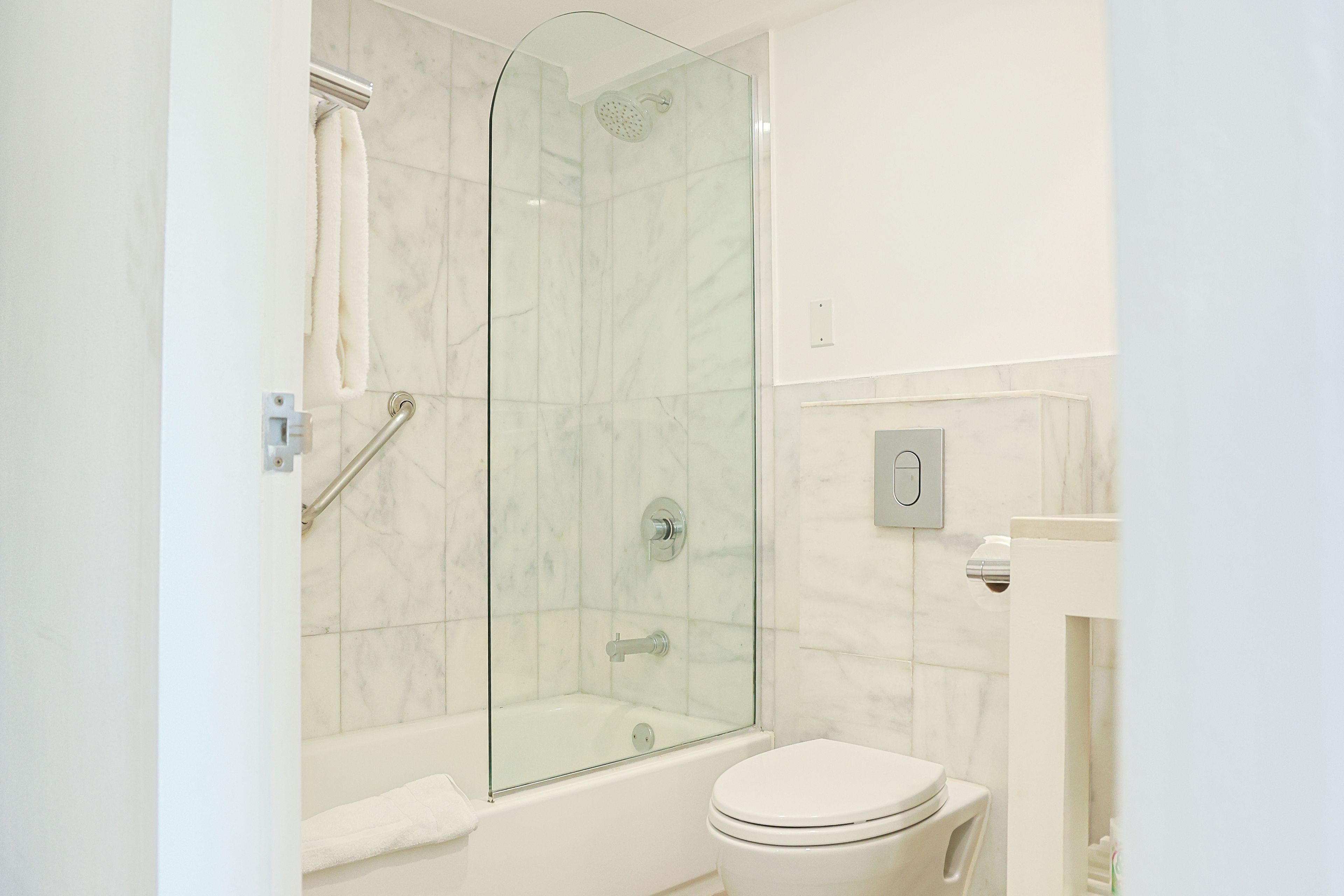 Un baño moderno con ducha envuelta en vidrio, una bañera blanca y un inodoro.