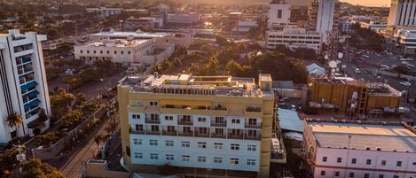 An aerial view of a cityscape with a prominent multi-story building featuring a flat roof and a central courtyard.