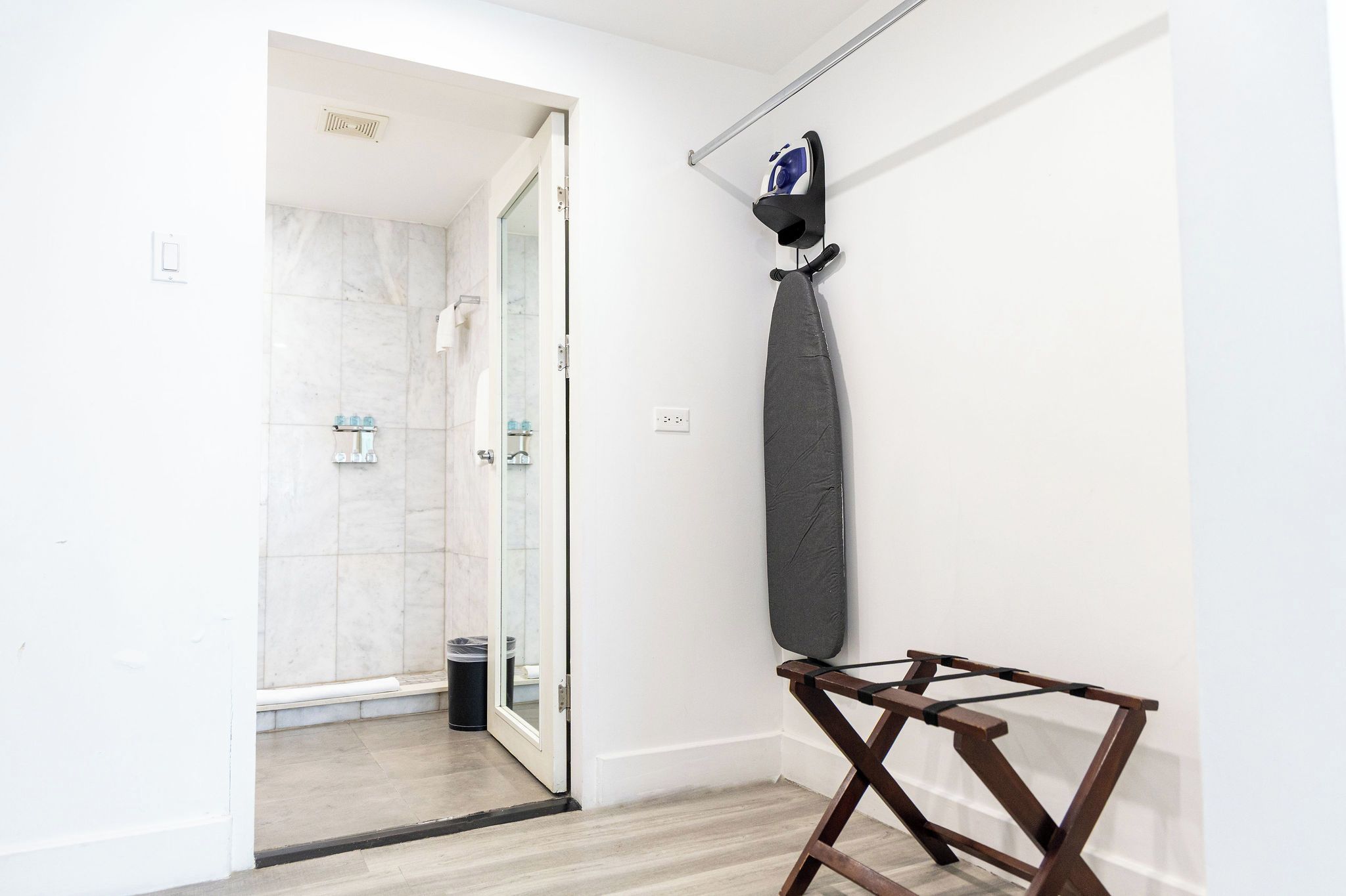 A bathroom with a shower, a towel rack, and a drying rack.
