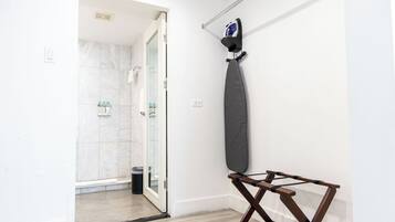 A bathroom with a shower, a towel rack, and a drying rack.